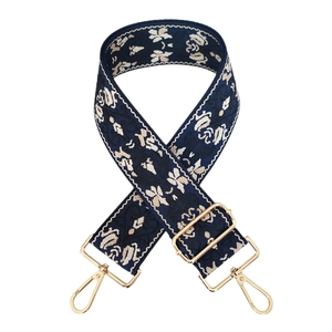 Dettaglio tracolla jacquard blu scuro con motivo floreale beige e ganci in metallo oro