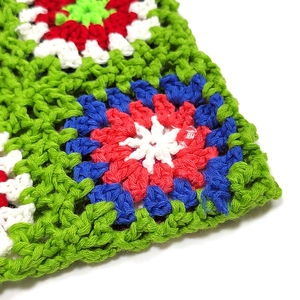 Detail of colorful handmade crochet granny square stitching on a vibrant tote bag