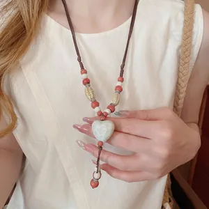 Collier ethnique avec pendentif cœur en céramique et cordon tressé sur modèle