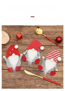 Detailed view of gnome-themed cutlery holders with red knit hats on a wooden table