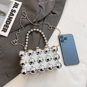 Silver metallic acrylic clutch bag with bead studs and chain strap shown with a smartphone