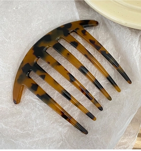 Close-up of tortoise shell pattern acetate 7-tooth hair comb on textured background