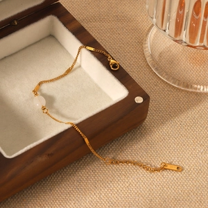 French vintage stainless steel gold bracelet with white stone on a wooden jewelry box