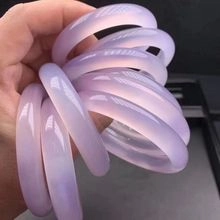 Close-up showing a hand holding several translucent lavender agate bangles