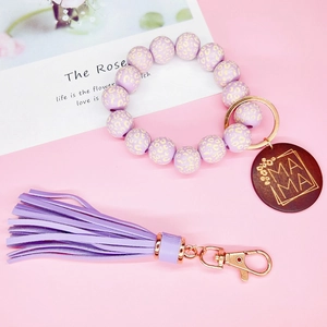 Détail du bracelet en perles lavande avec pompon en cuir et pendentif MAMA en bois