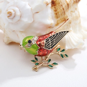 Close-up of bird brooch with red enamel, gold base and clear rhinestone details