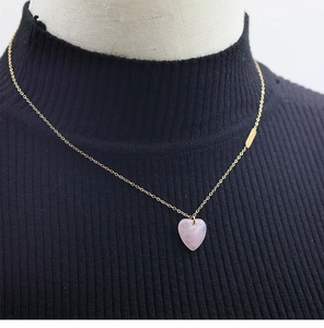 Close-up of pink heart-shaped natural stone pendant necklace on a gold chain