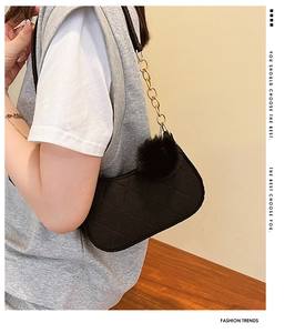 Détail du sac à bandoulière matelassé noir avec chaîne dorée et pompon en fausse fourrure