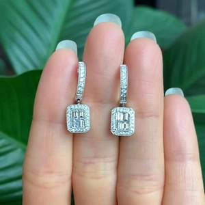 Close-up of rectangular moissanite hoop earrings with halo diamonds in silver metal