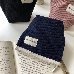 Corduroy makeup bags in navy, black and pink with fabric labels and zipper closures