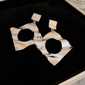 Detail of silver geometric earrings with a hammered liquid metal finish in a velvet box
