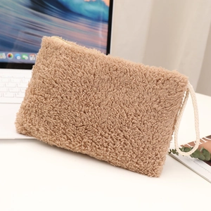 Close-up of camel plush pouch with soft faux shearling texture and ivory woven wristlet strap