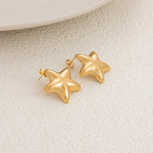 Macro shot of 18K gold plated star earrings showing 3D texture and brushed metal finish