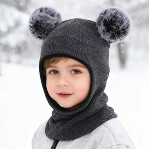 Detail of grey knitted baby hood with dual faux fur pom-poms and warm earflaps in snow