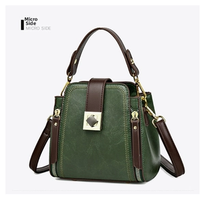 Detail view of dark green bucket bag with lychee texture leather and brown straps