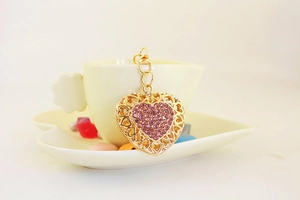 Detailed view of golden heart keychain with pink rhinestones on a heart-shaped cup