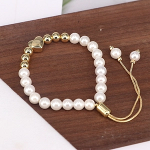 Macro detail of French retro pearl bracelet with gold heart charm and adjustable cord