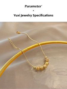 Close-up of golden transfer bead bracelet with snake chain on elegant silk background