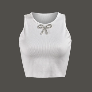 Close-up of white ribbed knit crop top featuring a sparkling rhinestone bow detail