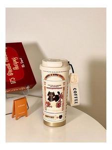 Close-up of cream white cat coffee tumbler with woven handle and cute black cat illustration