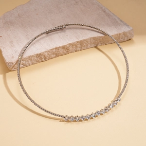 Detail of silver choker necklace with square-cut zircons on a natural stone background