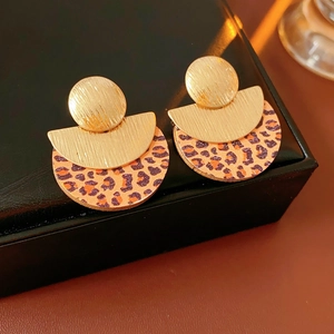 Macro view of vintage round earrings with gold textured metal and leopard print wood