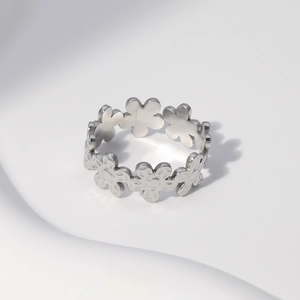Macro detail of silver daisy floral pattern on minimalist stainless steel open ring