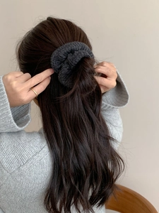 Vue détaillée du chouchou en maille gris foncé tenant les cheveux longs bruns avec style