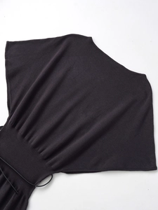 Detail of black knit dress featuring batwing sleeves and wide ribbed waist with tie belt