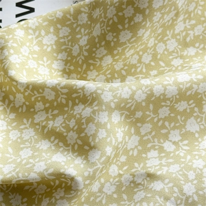 Close-up of yellow chiffon fabric with white daisy floral print and woven texture detail