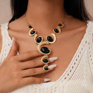 Close-up of chunky gold necklace featuring large oval black stones on model