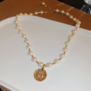 14K gold plated pearl necklace with vintage coin pendant on elegant white display tray