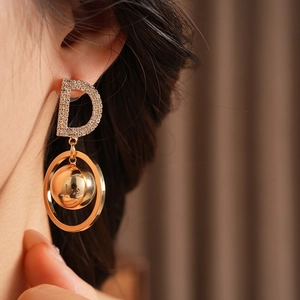 Macro shot of gold D-letter earring with sparkling rhinestones and metal ball detail