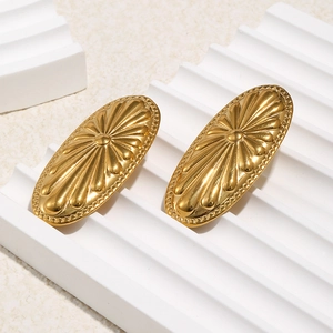 Goldene ovale Edelstahlohrringe mit radialer Blütenstruktur auf Keramikständer