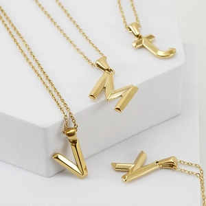 Golden 18K titanium steel necklaces featuring 3D letter J, M, V, Y pendants on a white pedestal