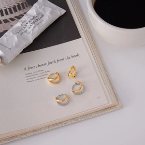 Macro of four titanium steel hoop earrings arranged on an open book with coffee