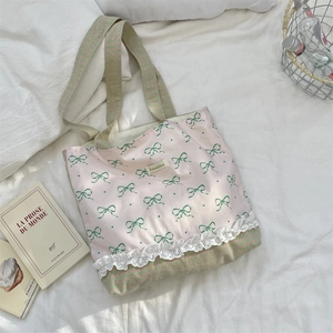 Detail of pink canvas tote with green bow patterns, plaid trim, and white lace borders