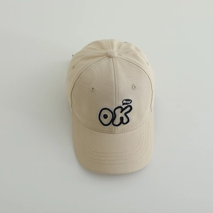 Detail of embroidered OK and good bubble on beige cotton baseball cap for kids