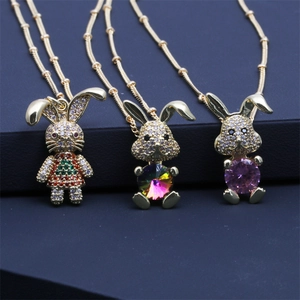 Close-up of golden bunny pendants with colorful micro-inlaid zircons on blue background