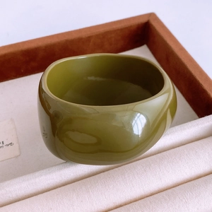 Gros plan d'un large bracelet en résine acrylique vert mousse avec une finition polie lisse
