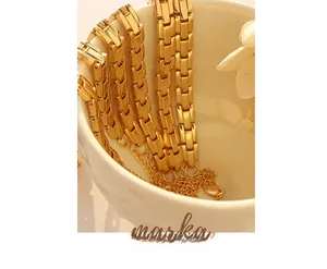 Polished gold titanium steel watch-strap chain bracelet on white ceramic mug with dried flowers
