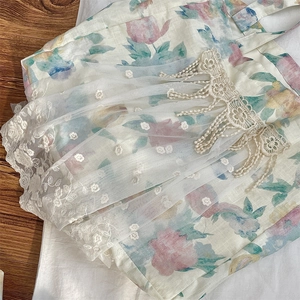 Close-up of floral linen tote with mesh overlay and delicate white lace fringe details