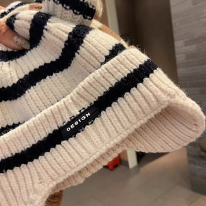 Close-up of thick knit black and white striped baby hat showing texture and design label