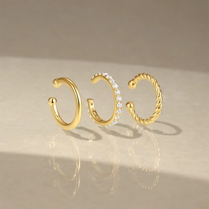 Detailed view of three-piece gold S925 sterling silver ear cuff set on stone surface
