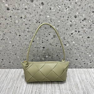 Light green woven leather handbag with knot strap on a textured grey background