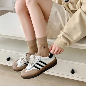 Close-up of light brown ribbed cotton socks featuring a small bee embroidery on the side