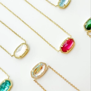 Elegant gold necklaces with assorted natural stone oval pendants on a white surface