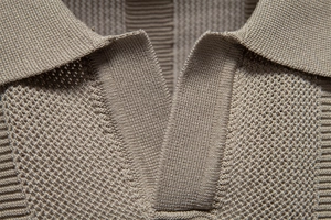 Macro detail of khaki knit polo shirt showing breathable mesh texture and V-neck stitching