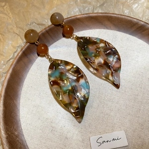 Macro detail of vintage acetate leaf earrings showing vibrant marbled texture and golden links
