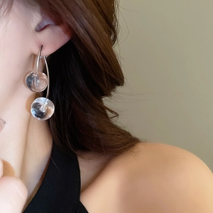 Detailed view of silver cherry style earrings with double transparent spheres on a model
